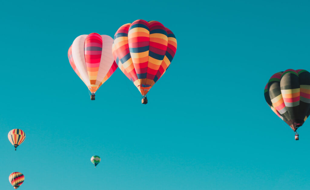 Färgglada luftballonger på blå himmel.